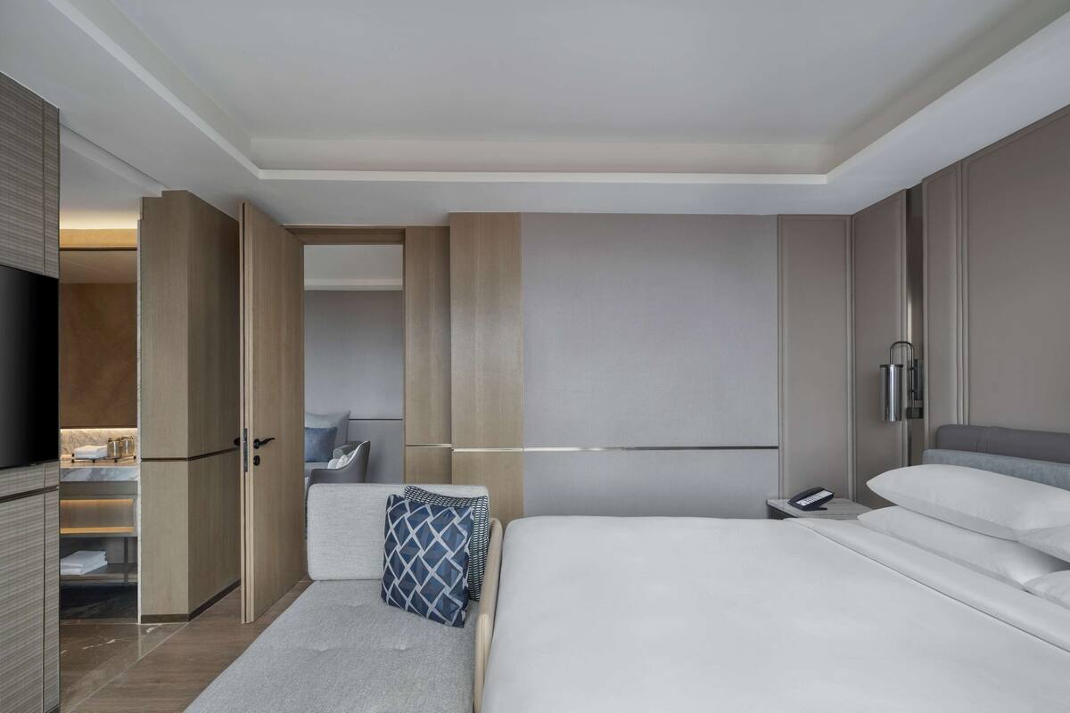 Een moderne hotelkamer met een groot bed, een nachtkastje met telefoon, een kledingkast en een televisie.