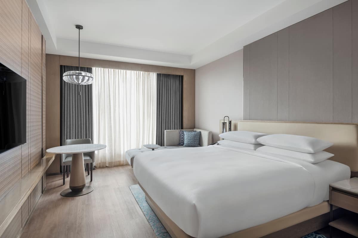 Een moderne hotelkamer met een groot bed, nachtkastjes, een ronde tafel en een televisie.