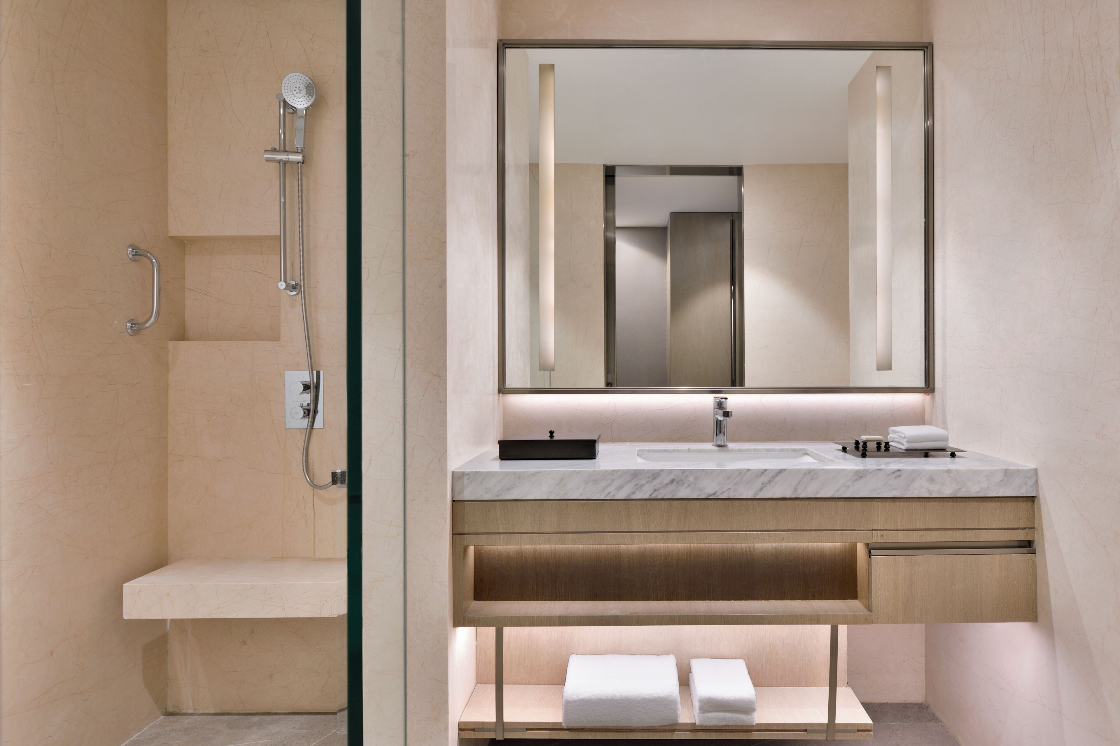 A modern bathroom with a shower, a sink, a mirror, and a towel rack.