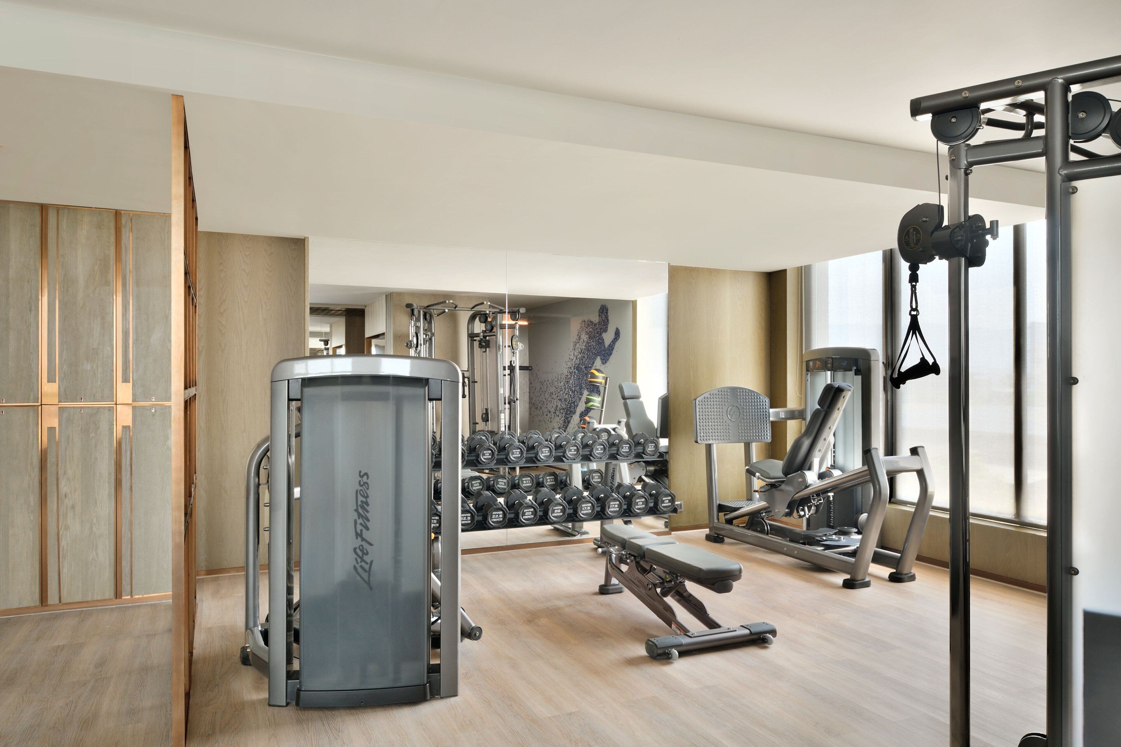 Une salle de sport moderne équipée de machines de cardio, d’appareils de musculation et d’haltères.