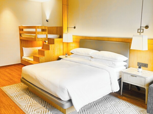 A modern hotel room with a large bed, wooden headboard, bedside tables, and a patterned rug. - Katra Marriott Resort & Spa (Reasi)