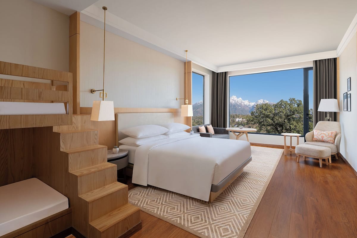 Una habitación de hotel moderna con una cama grande, un área de descanso con vistas y una escalera.