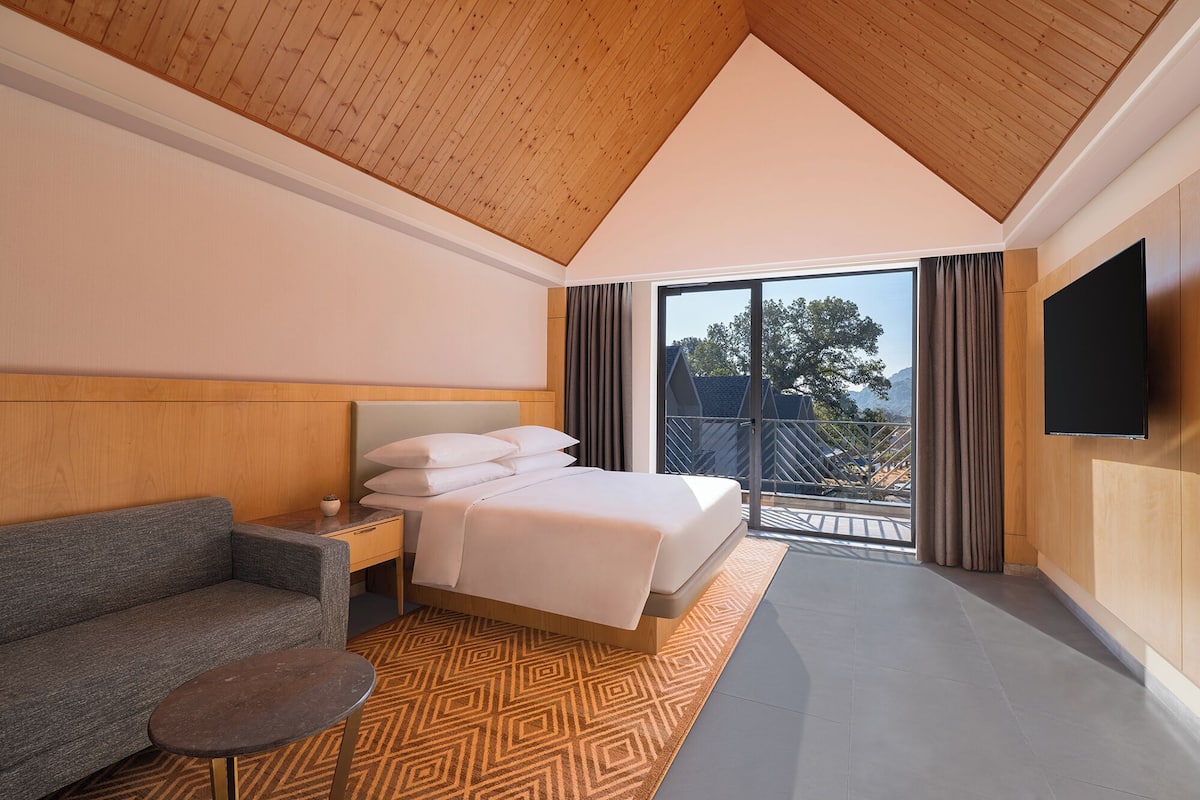 Una habitación de hotel moderna con una cama, un sofá, una mesita y un televisor.