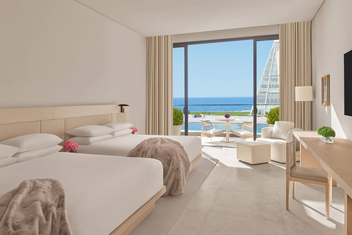 A hotel room with a large bed, a desk, and a view of the ocean.