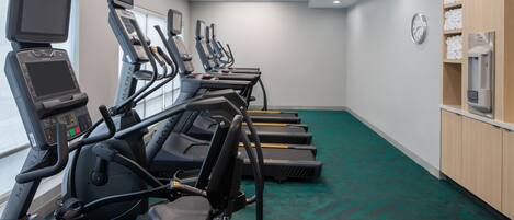 A fitness room with treadmills, exercise bikes, and a clock on the wall.