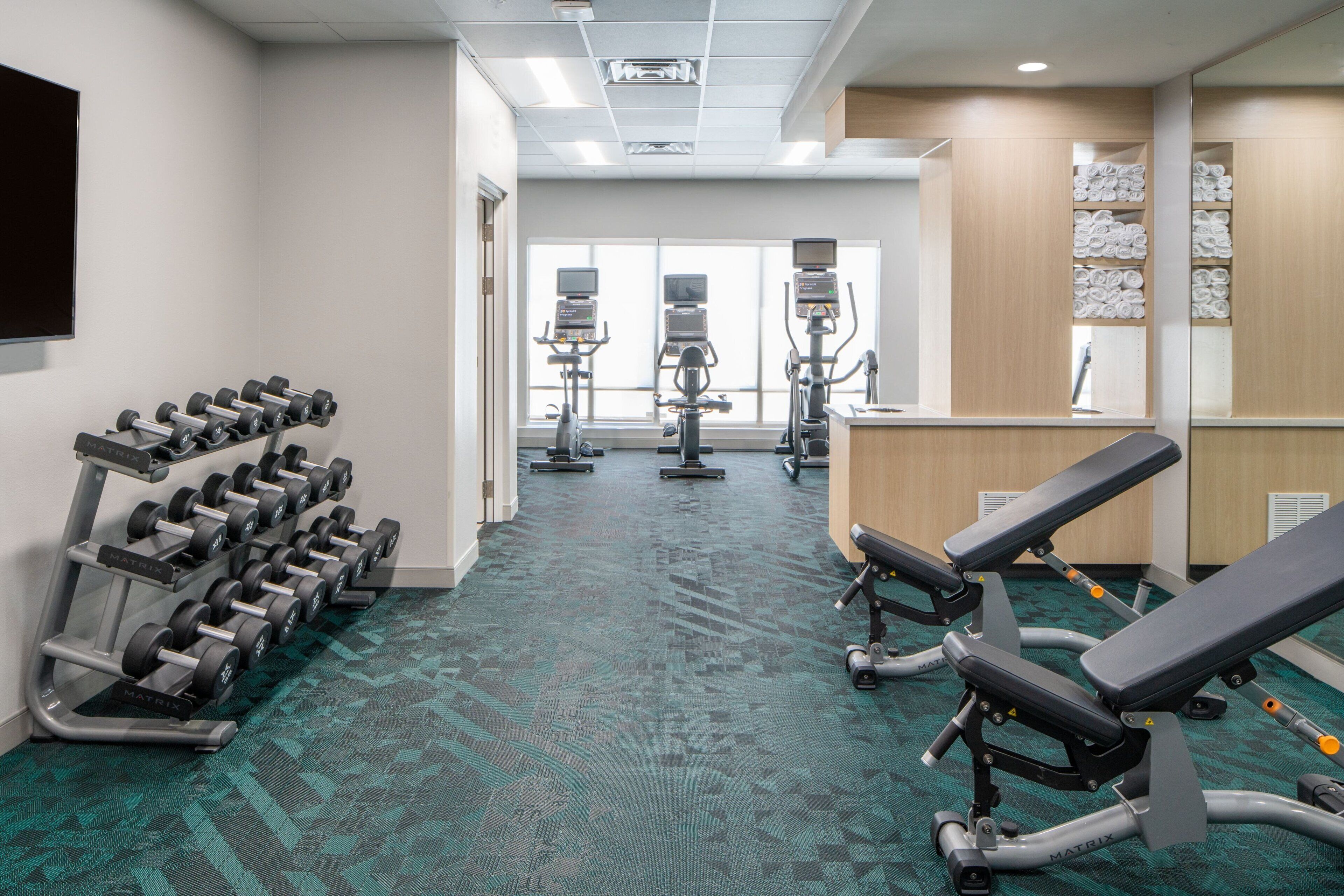 A gym with exercise equipment, a treadmill, and a bench.