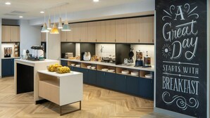 A modern kitchen with wooden cabinets, a white countertop, and pendant lighting. There is a chalkboard with the text "A Great Day Starts with Breakfast". - Towneplace Suites Pensacola West I-10 (Pensacola)