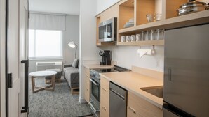 A compact kitchen with a microwave, oven, and refrigerator. There is a small dining area with a table and chairs. - Towneplace Suites Pensacola West I-10 (Pensacola)