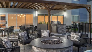 Une terrasse extérieure avec des sièges en pierre, un foyer et un espace barbecue.