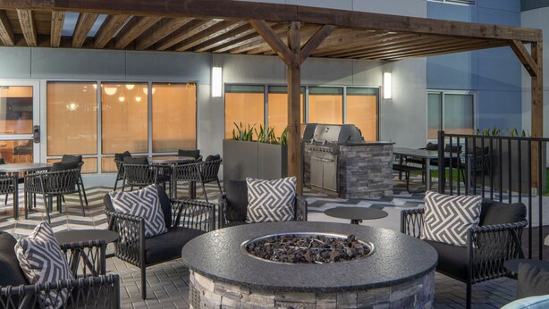 An outdoor patio with stone seating, a fire pit, and a grill area. - Towneplace Suites Pensacola West I-10 (Pensacola)