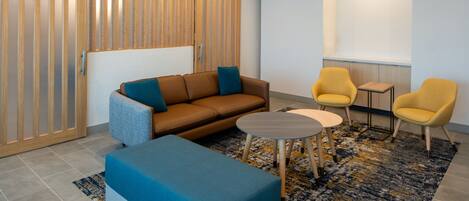 A modern lounge area with a sofa, two armchairs, a small table, and a patterned rug.