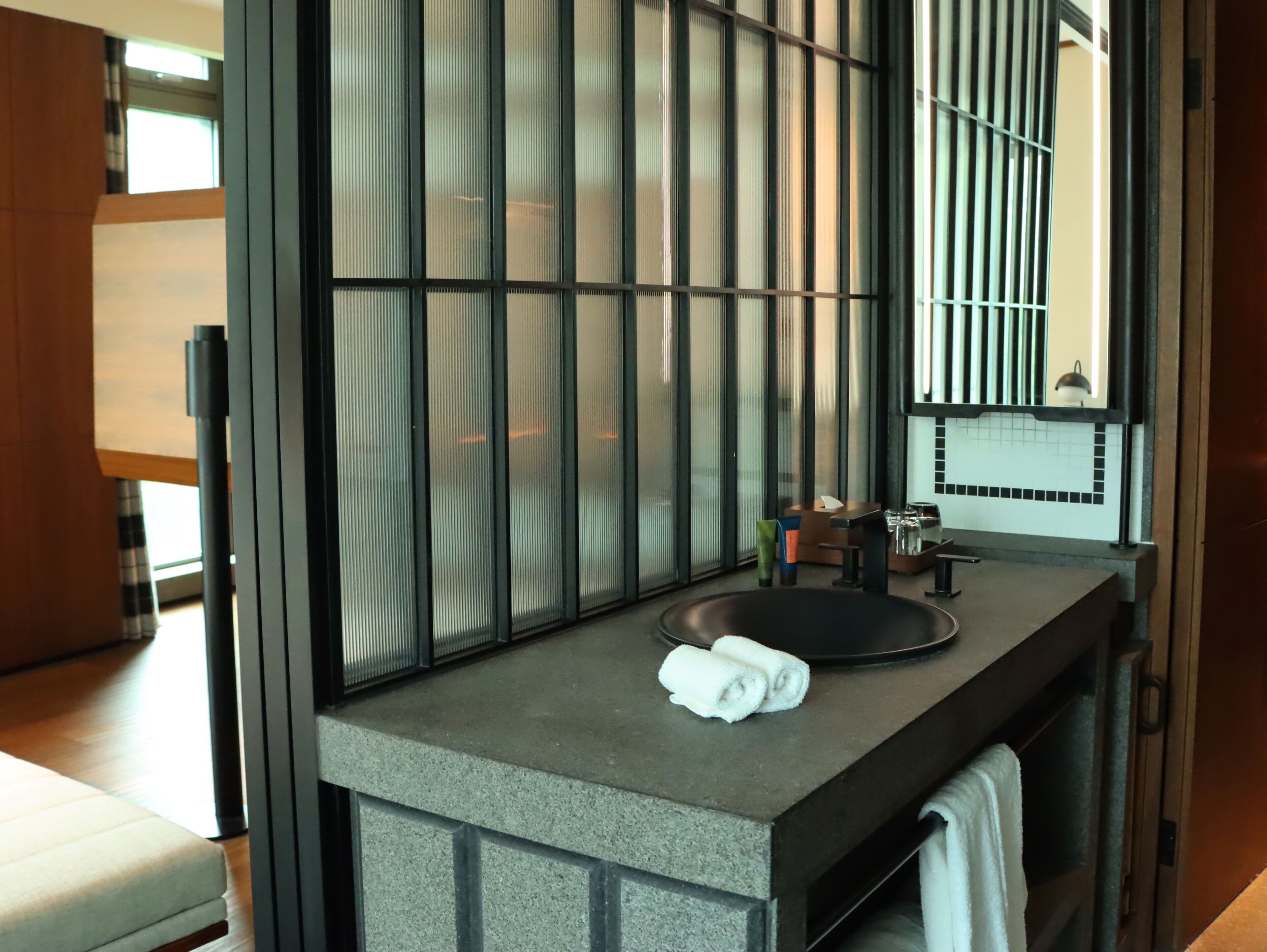 A modern bathroom with a large window, a sink, and a mirror.