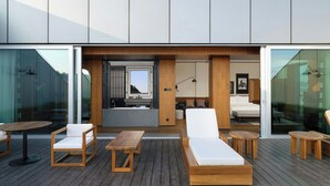 A modern outdoor deck with wooden furniture, a sofa, and a dining table.