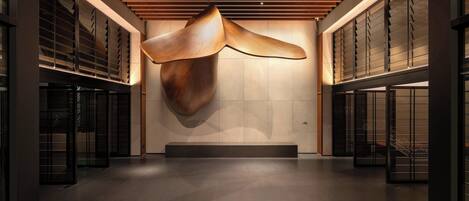 A modern interior with a large wooden sculpture, recessed lighting, and a minimalist design.