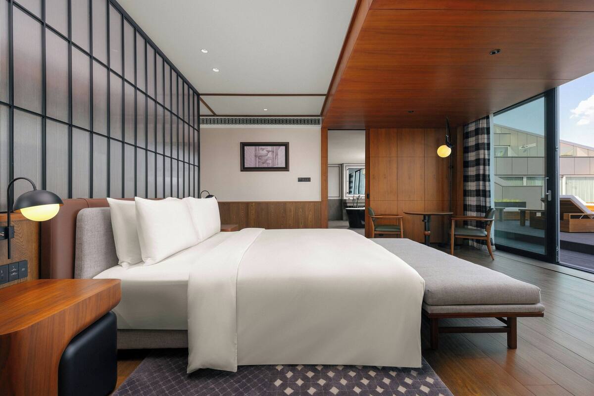 A modern hotel room with a large bed, a desk, and a seating area.