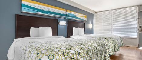 Una habitación de hotel con una cama grande, un cabecero con interruptor de luz y una ventana con persianas.