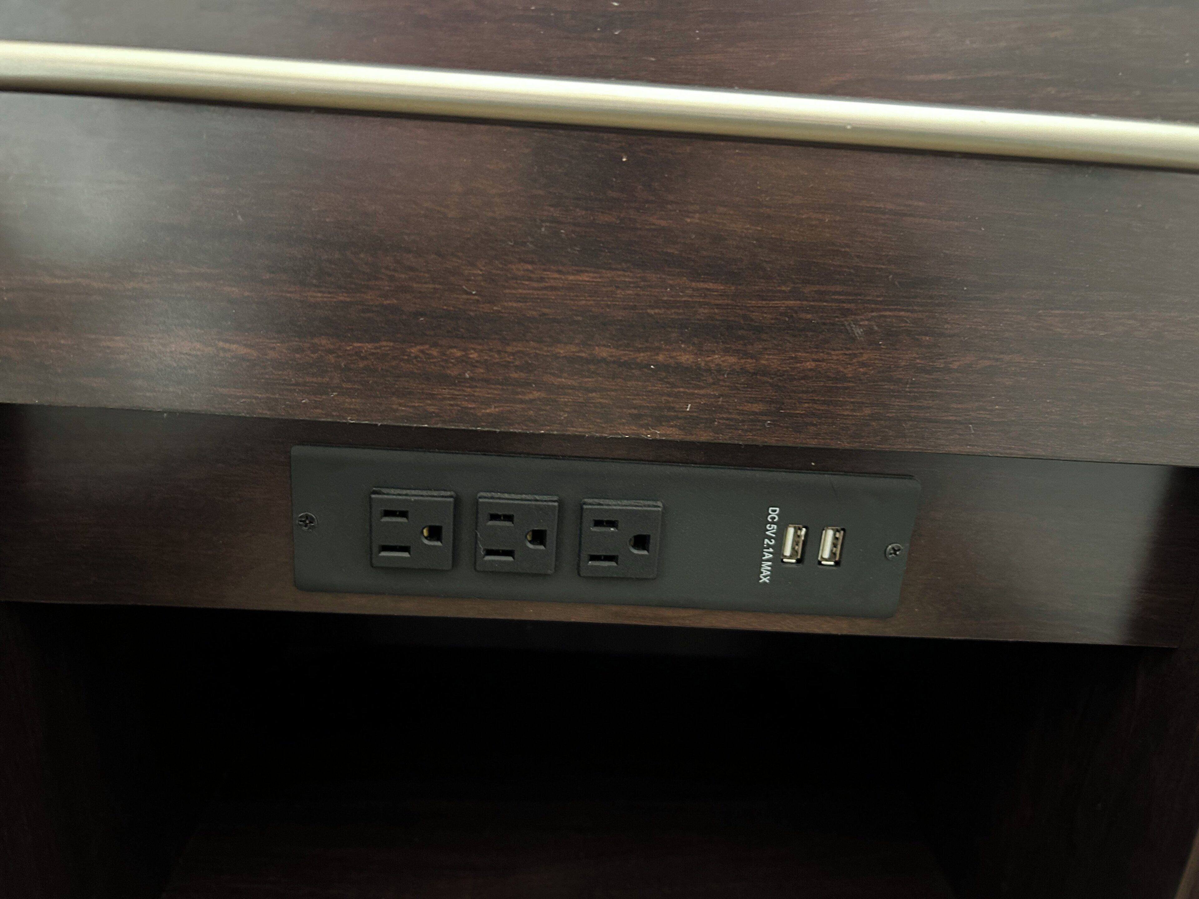 A dark wooden surface with a cable and a power strip with two USB ports and a 3.5mm audio jack.