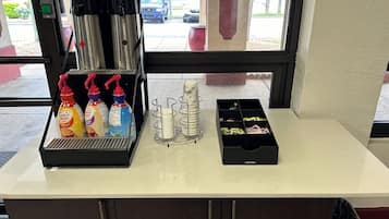 Een balie met een koffiehoek, kruidenbakjes en een prullenbak.