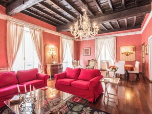 A room with a red sofa, a glass coffee table, and a chandelier.