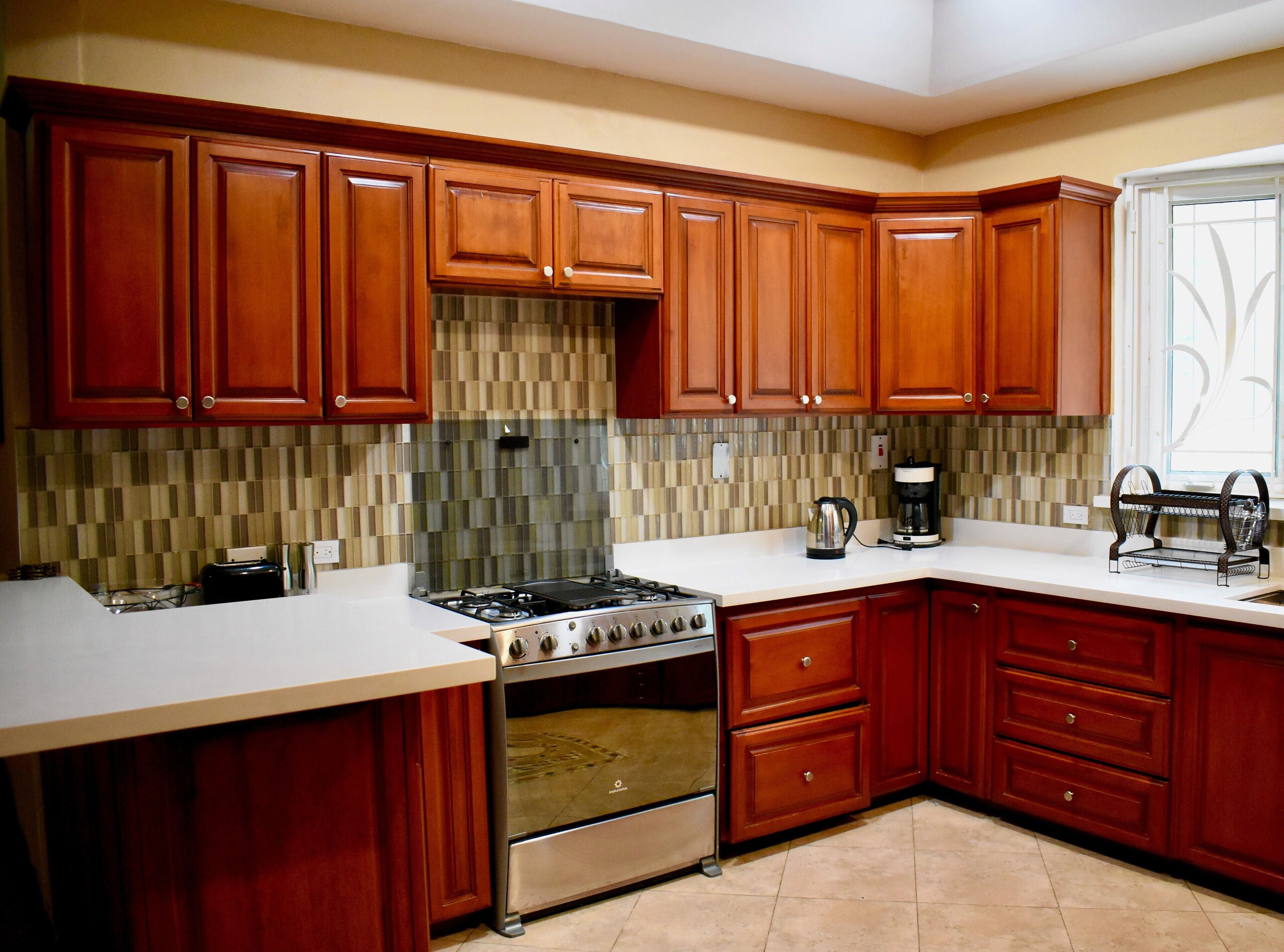 A modern kitchen with wooden cabinets, a stainless steel stove, and a tiled backsplash.