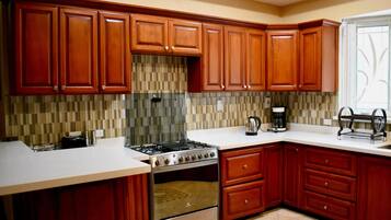 A modern kitchen with wooden cabinets, a stainless steel stove, and a tiled backsplash.