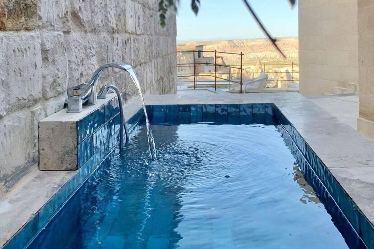 A swimming pool with a stone wall and a view of a mountainous landscape.