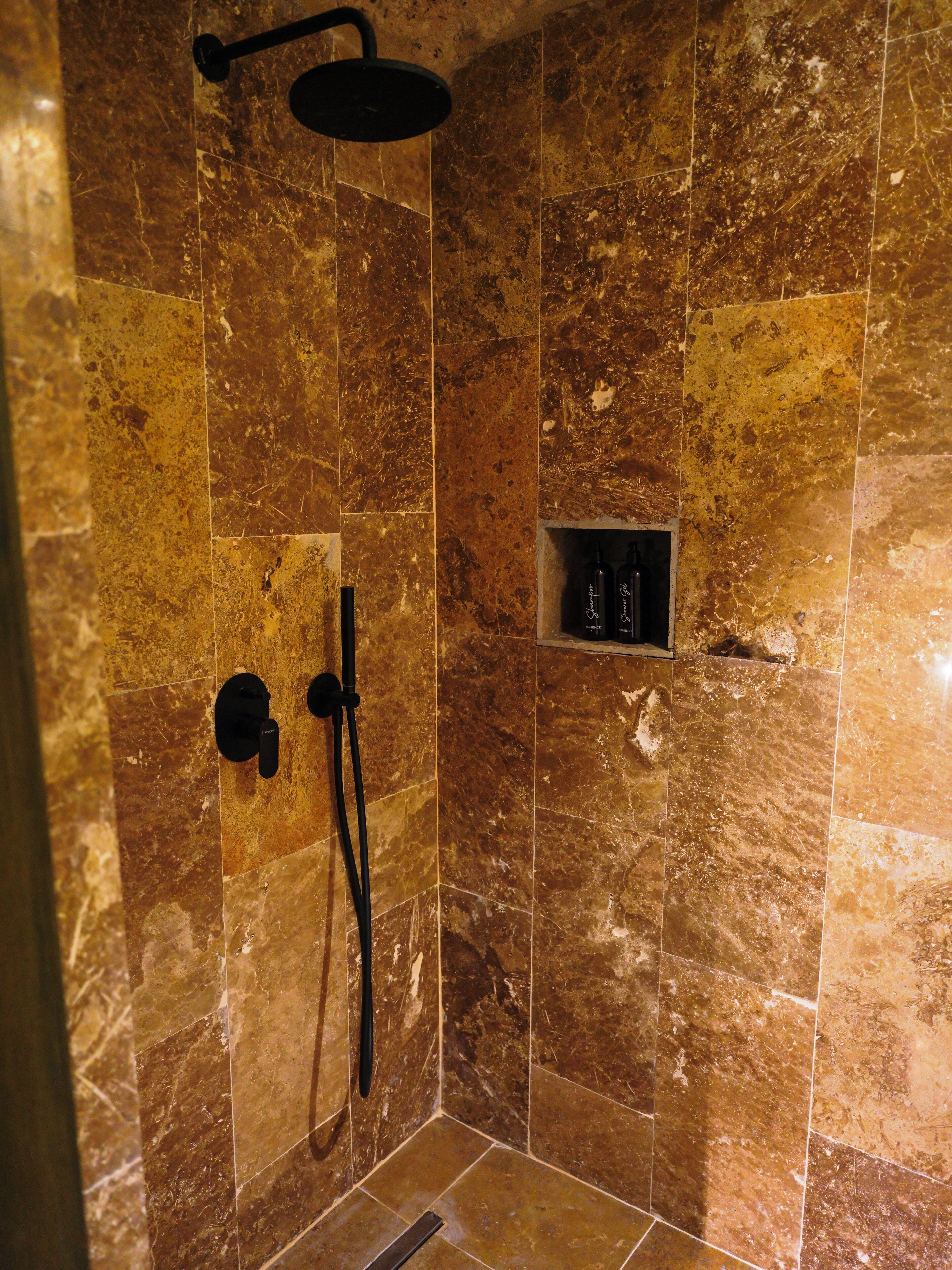 A shower with a handheld showerhead and a wall-mounted control.