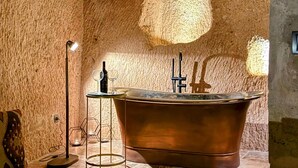 A bathroom with a freestanding bathtub, a floor lamp, and a hexagonal mirror. - Very Peri Cappadocia - The Lifestyle Luxury Design Hotel  (Nevsehir)