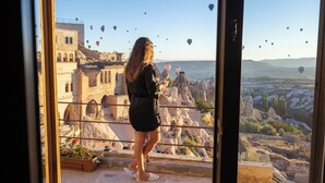 A person standing by a glass door overlooking a cityscape with historic buildings and a view of the sea. - Very Peri Cappadocia - The Lifestyle Luxury Design Hotel  (Nevsehir)