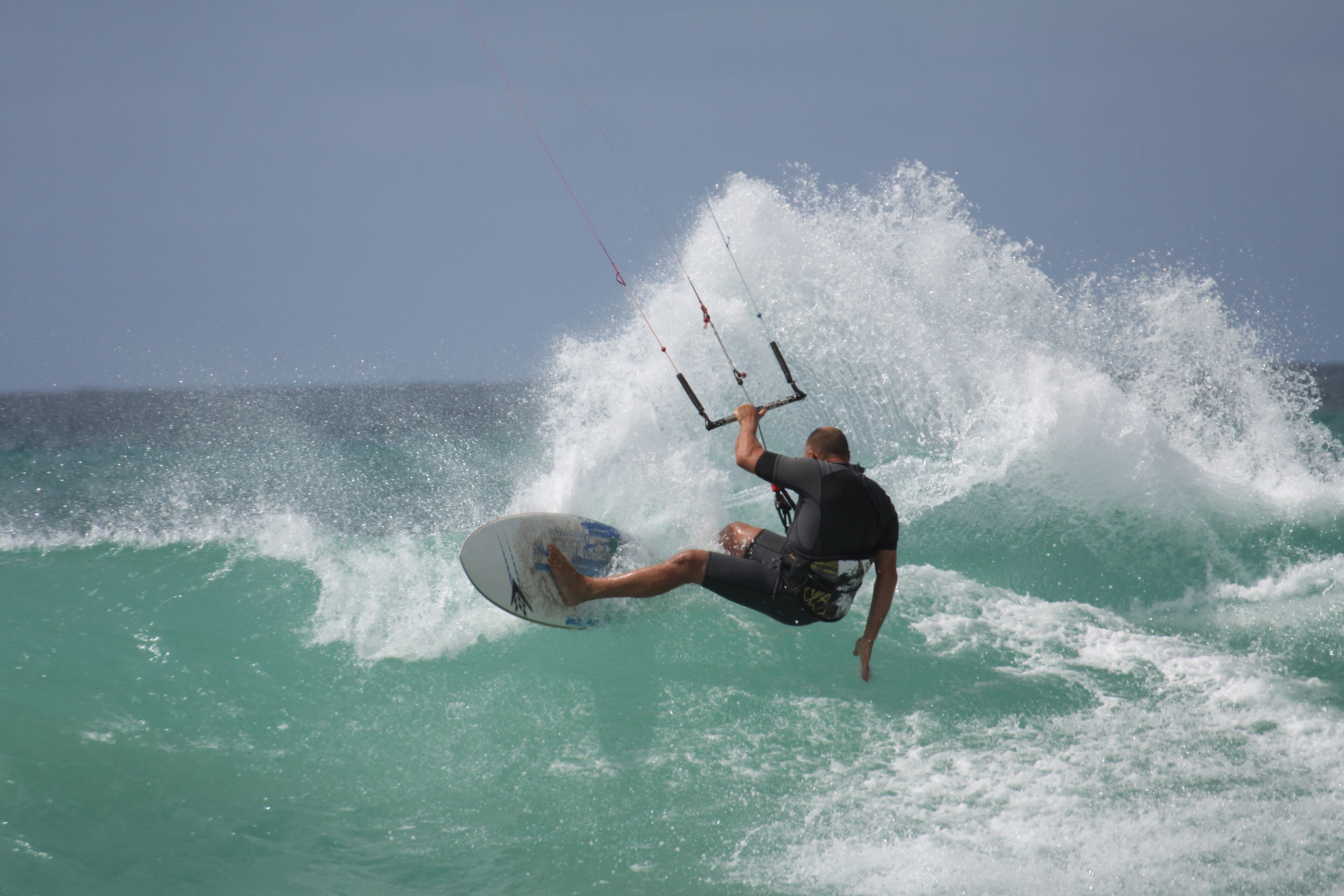 Iemand kitesurft op een golf.