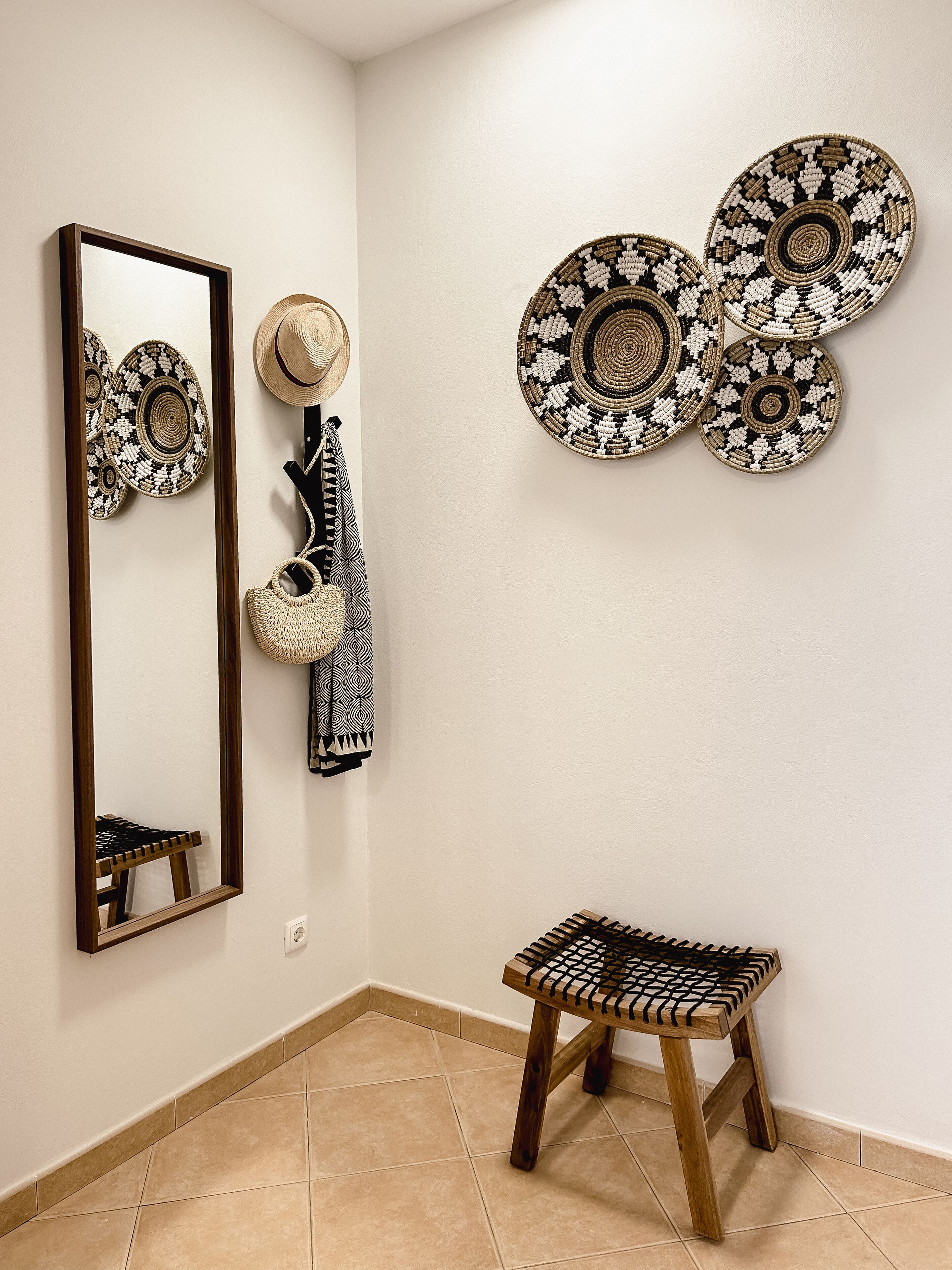Un coin de pièce avec un miroir, un panier en osier et un petit tabouret.