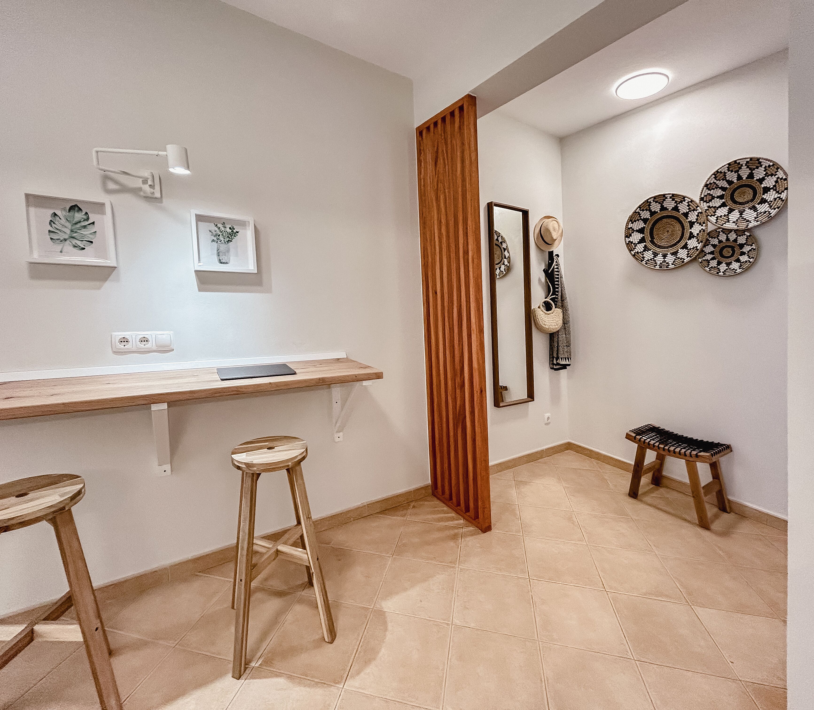 Un baño con tocador de madera, dos taburetes, un espejo y placas decorativas en la pared.
