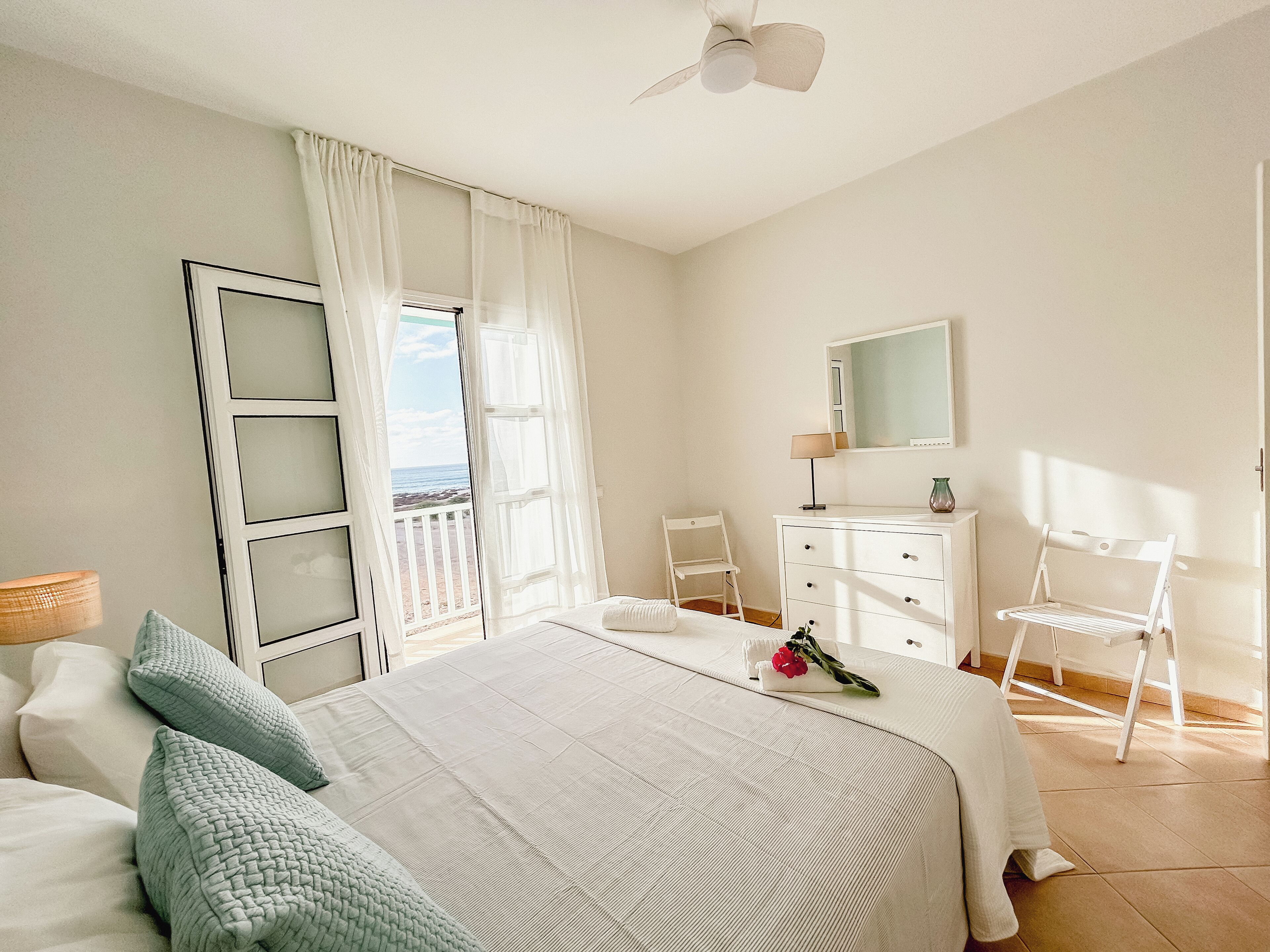 Une chambre à coucher avec un lit, une commode, une chaise et une fenêtre avec des rideaux.
