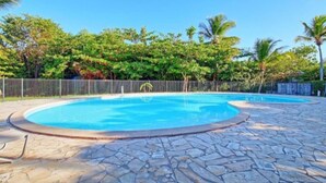A swimming pool with a stone deck, surrounded by a fence and lush greenery. - " Casanova House" à 2 Minutes à Pied des Restaurants et 5 Minutes de la Plage (Saint Martin)