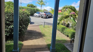 A pathway leading to parked cars, surrounded by lush greenery and palm trees. - " Casanova House" à 2 Minutes à Pied des Restaurants et 5 Minutes de la Plage (Saint Martin)