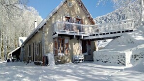 Een chalet met een balkon, omringd door met sneeuw bedekte bomen en een heldere lucht.