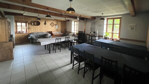 Een ruime keuken met houten balken, een eethoek met meerdere tafels, en een gezellige zithoek.