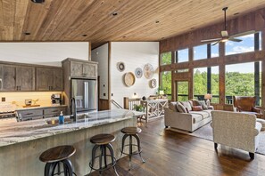 A spacious kitchen with a large island, wooden cabinets, and a view of the outdoors. - Brand NEW Luxury Chalet! Summer Sale! (Epworth)