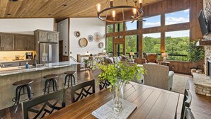 A spacious kitchen with a central island, wooden ceiling, and large windows offering a view of the outdoors. - Brand NEW Luxury Chalet! Summer Sale! (Epworth)