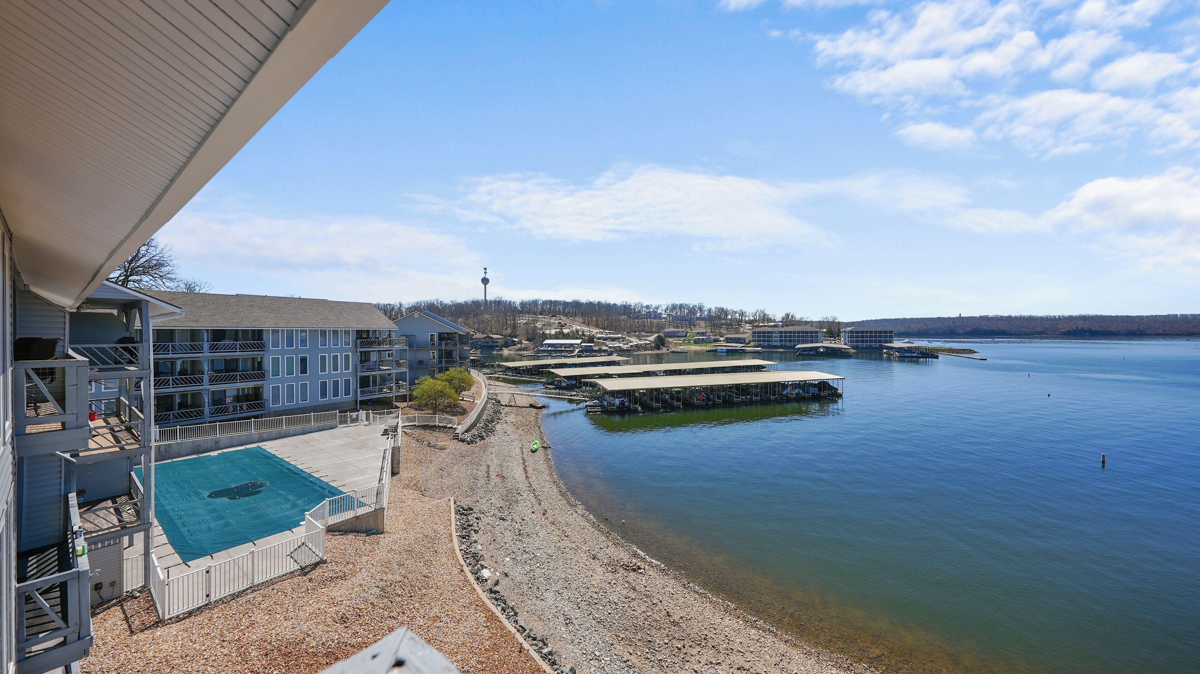 A waterfront hotel with a swimming pool, docked boats, and a view of the lake.