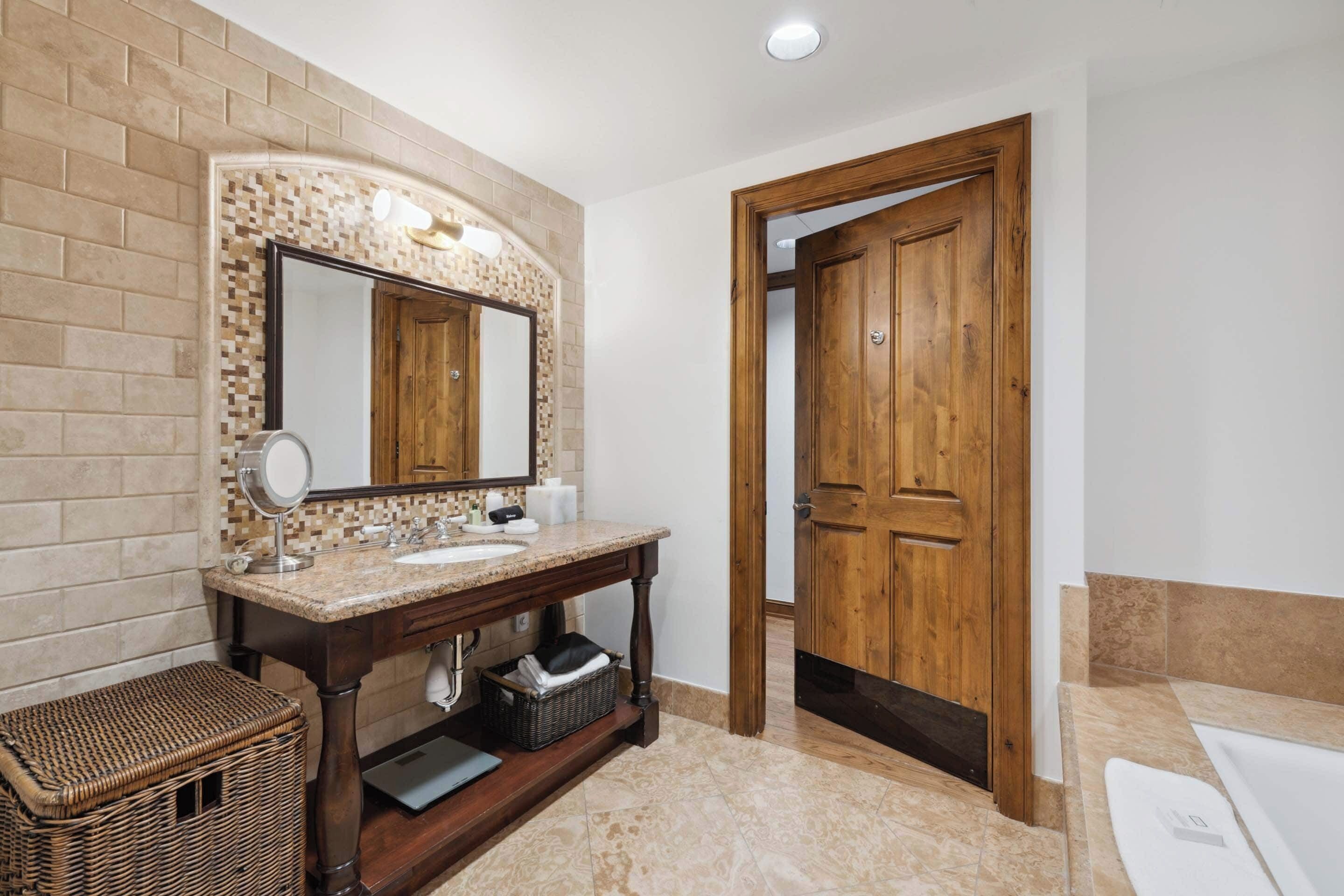 Un baño con tocador de madera, un espejo grande, un lavamanos y una bañera.