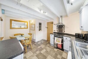 Een kleine keuken met een eettafel, een fornuis en een spoelbak.