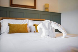 A neatly made bed with white linens and a single white towel draped over the side. - Cosy Country Cottage Sleeps 4 (Kirkbymoorside)