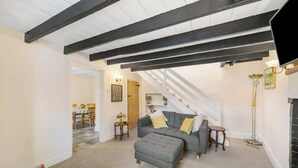 A living room with a sofa, ottoman, and a staircase. - Cosy Country Cottage Sleeps 4 (Kirkbymoorside)