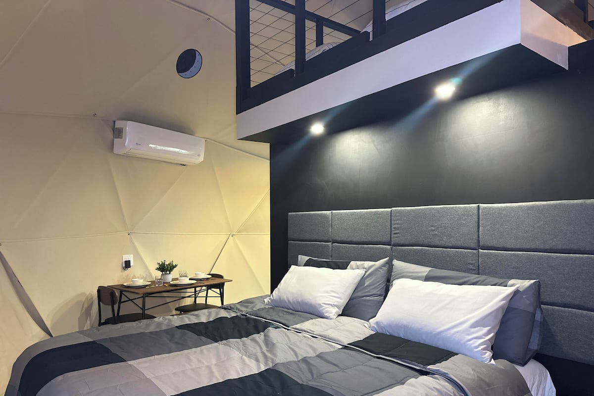 A modern bedroom with a large bed, a nightstand, and a ceiling fan.