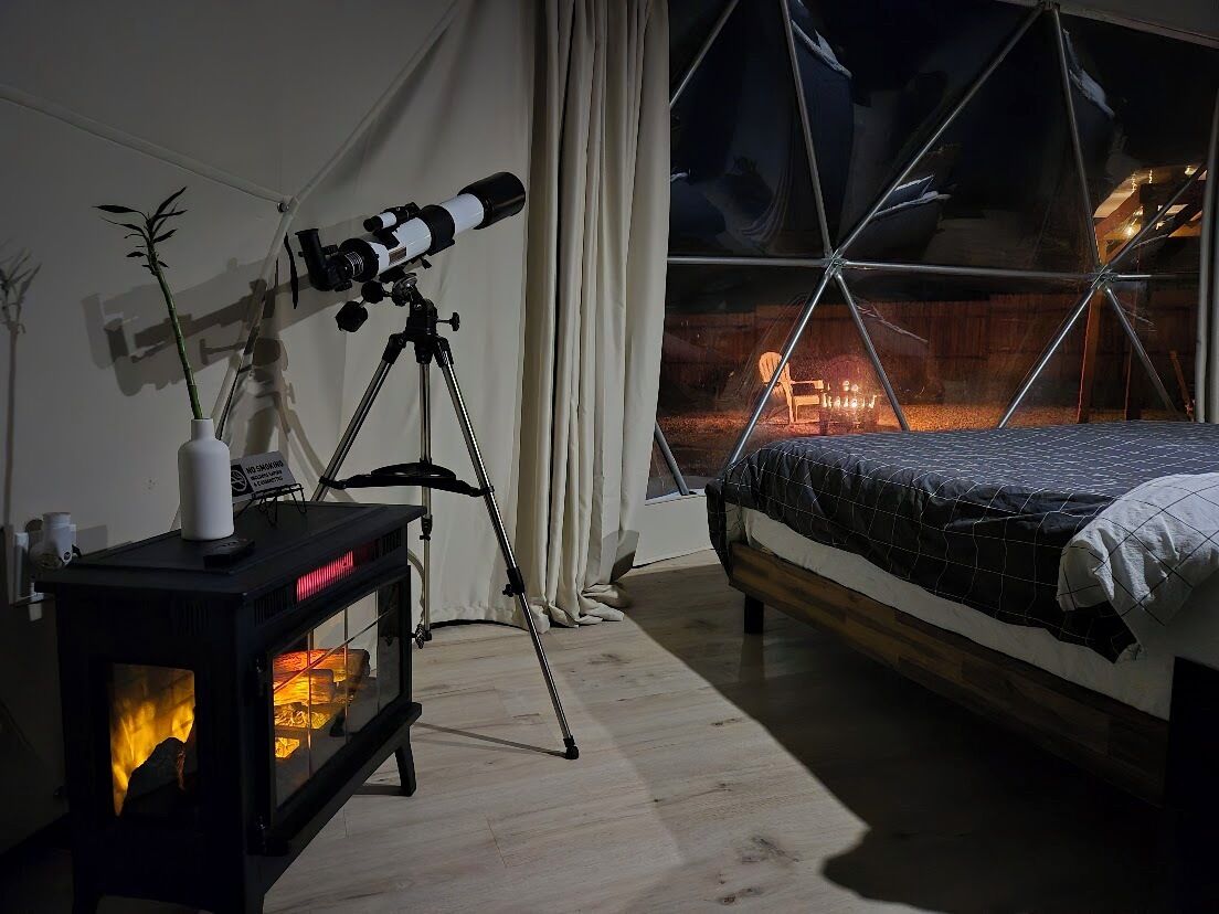 Una camera da letto con un letto, un telescopio e un camino a legna.
