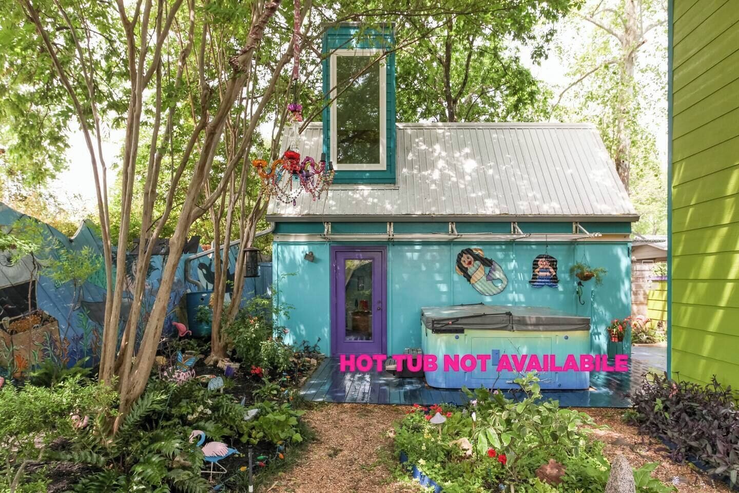 Una casa pequeña y colorida con una puerta morada y un letrero que indica "HOT TUB NO DISPONIBLE".