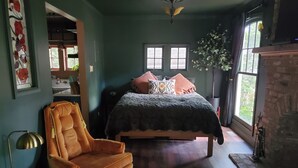 Een gezellige slaapkamer met een bed, een stoel, een vloerkleed en een open haard.