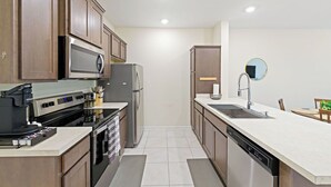 Une cuisine moderne dotée de meubles en bois, d’appareils électroménagers en acier inoxydable, d’un four encastré et d’un lave-vaisselle.