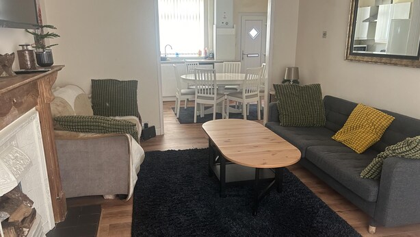 Uma sala de estar com sofá, mesa de centro e um espaço de jantar com cadeiras e mesa.